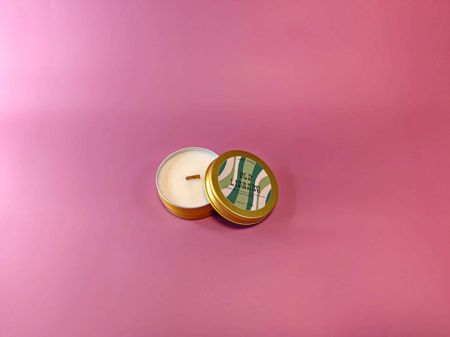 Gouden geurkaars in blik met label 'Old Library' op roze achtergrond, cadeau idee.