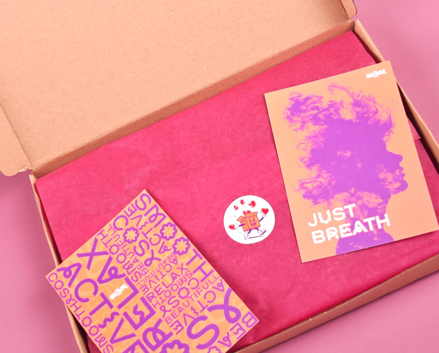 Open cadeaubox met roze inpakpapier, kleurrijke kaartjes en sticker, perfect cadeau.