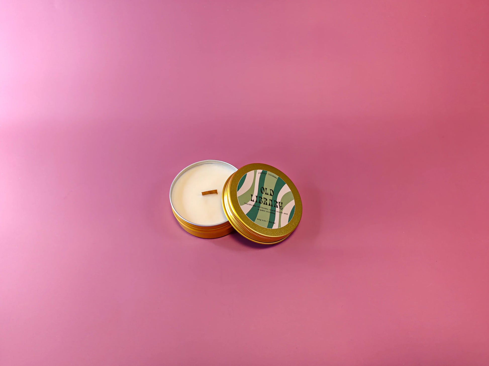 Gouden geurkaars in blik met label 'Old Library' op roze achtergrond, cadeau idee.