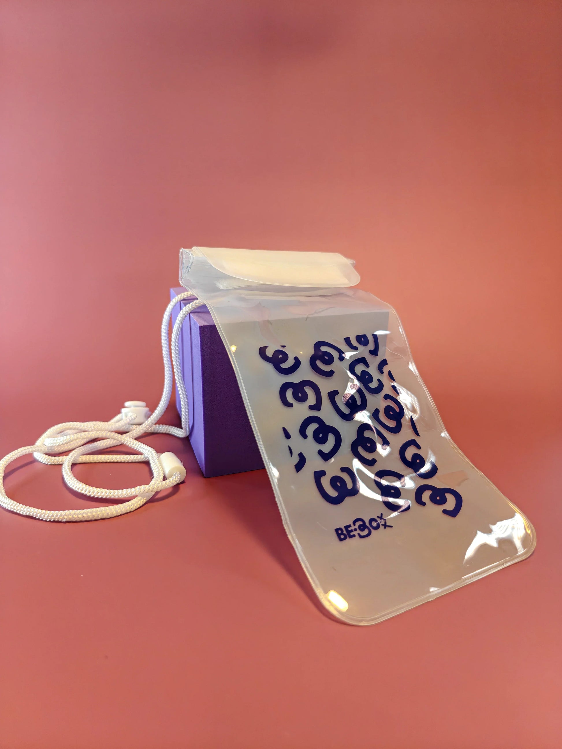 Paarse cadeauverpakking met doorzichtig waterdicht tasje, wit koord, op roze ondergrond