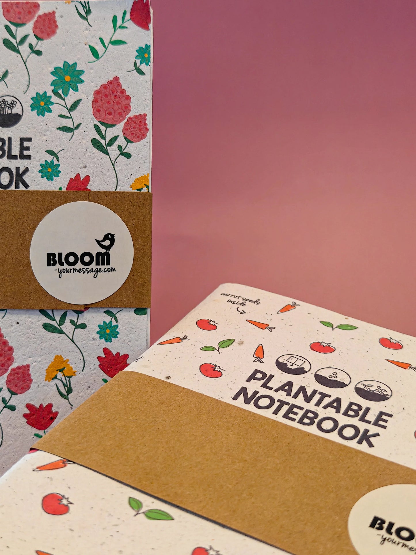 Duurzaam plantbaar notitieboek met bloemen- en groentedesigns tegen roze achtergrond