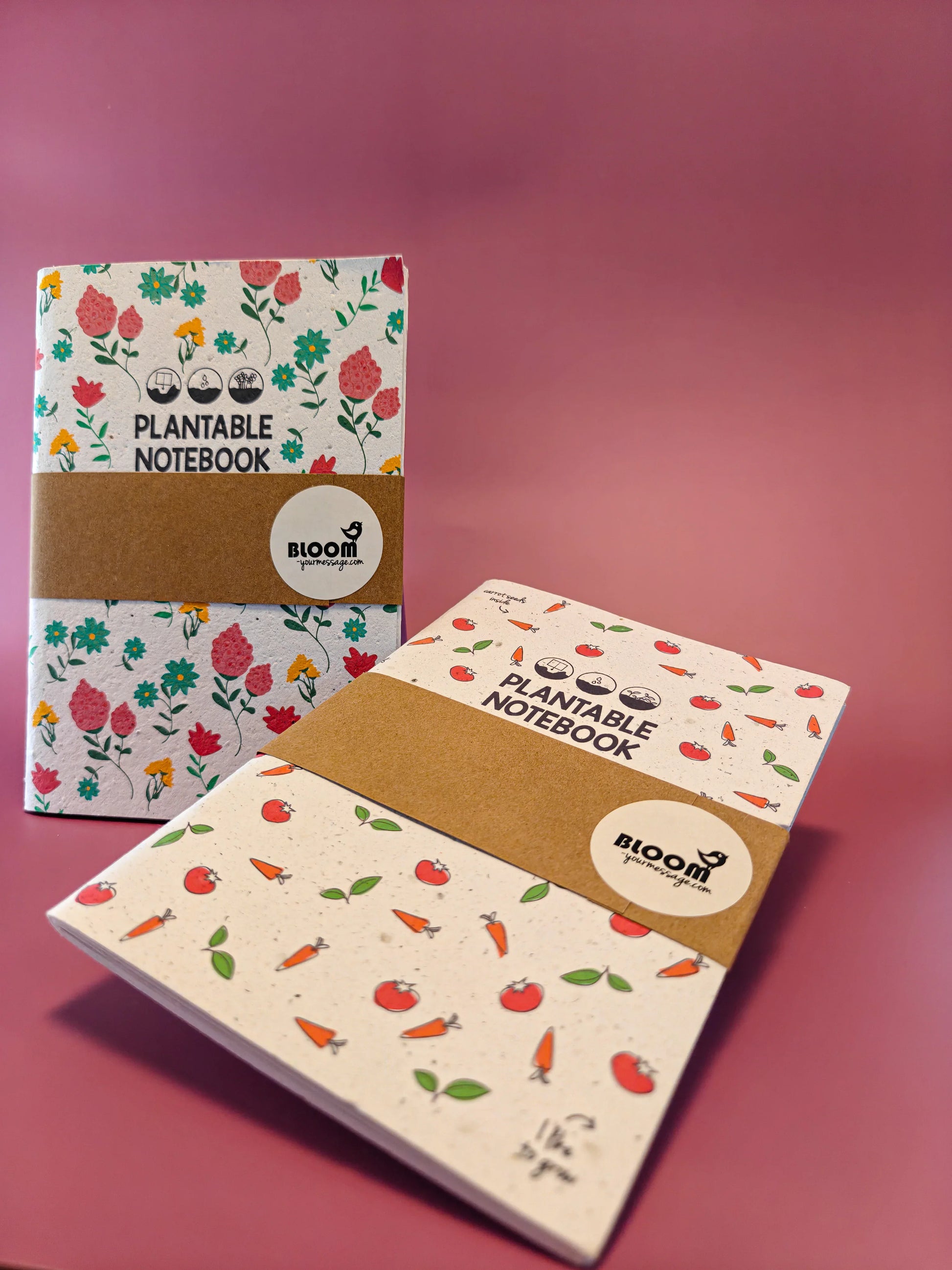 Twee plantbare notitieboekjes met bloemen- en groentepatronen op roze ondergrond