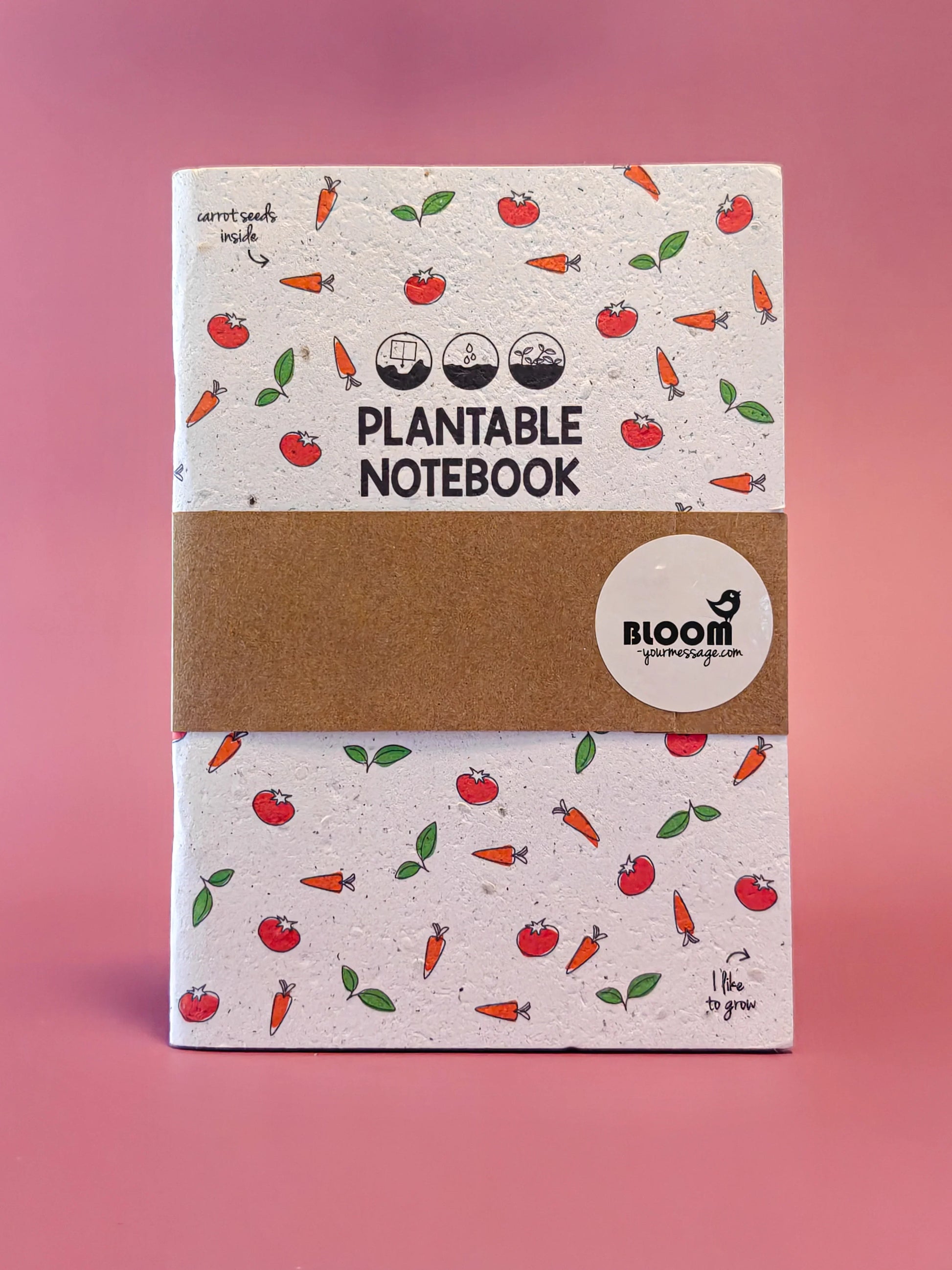 Plantbaar notitieboek met wortel- en tomatenillustraties tegen roze achtergrond, duurzaam cadeau