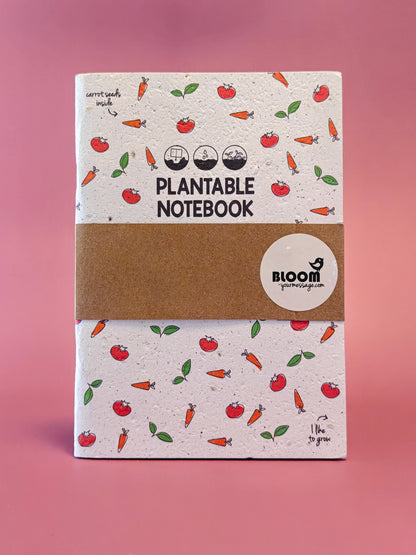Plantbaar notitieboek met wortel- en tomatenillustraties tegen roze achtergrond, duurzaam cadeau