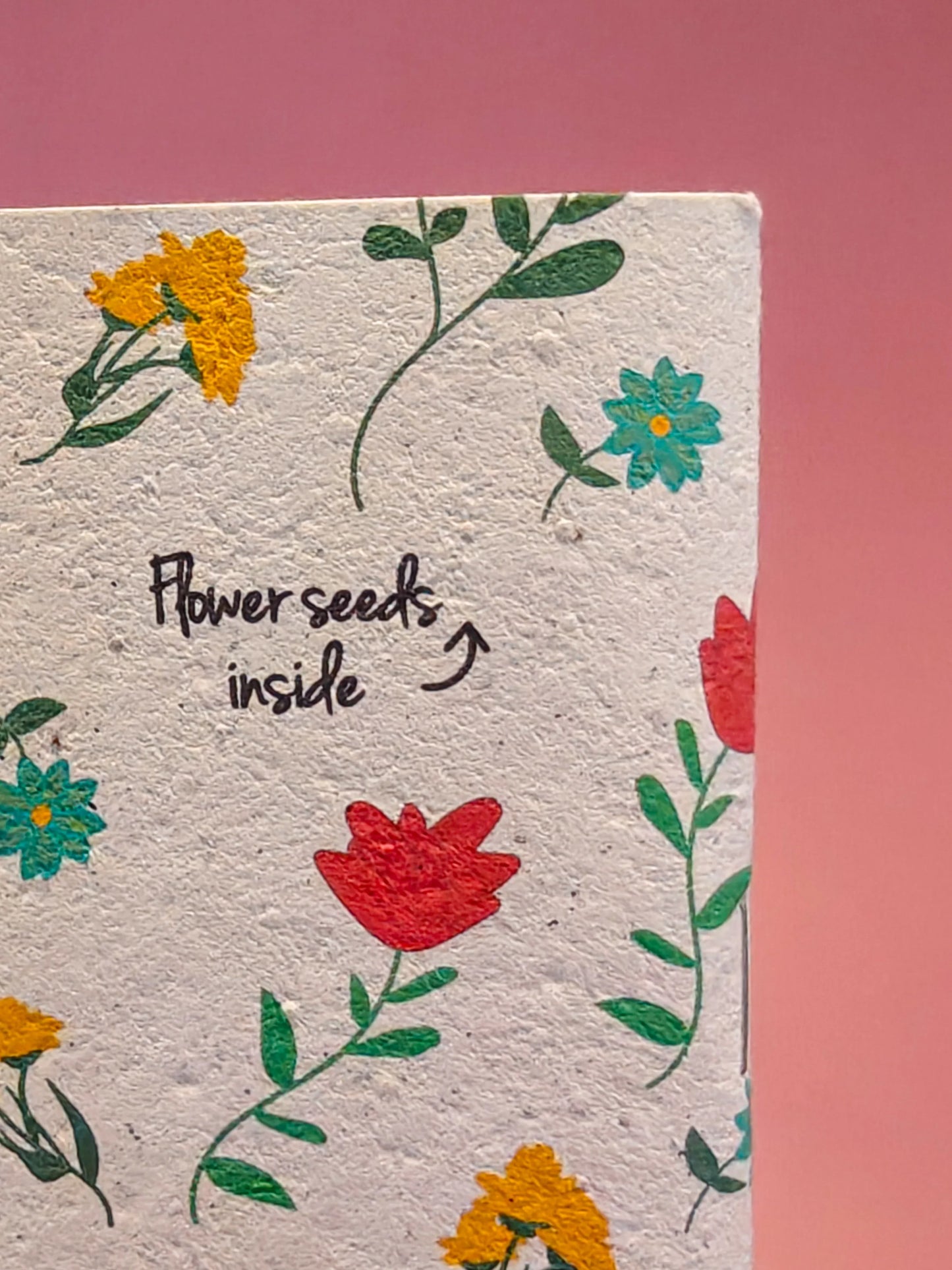 Duurzame kaart met bloemenmotief en tekst 'Flower seeds inside' op roze achtergrond.