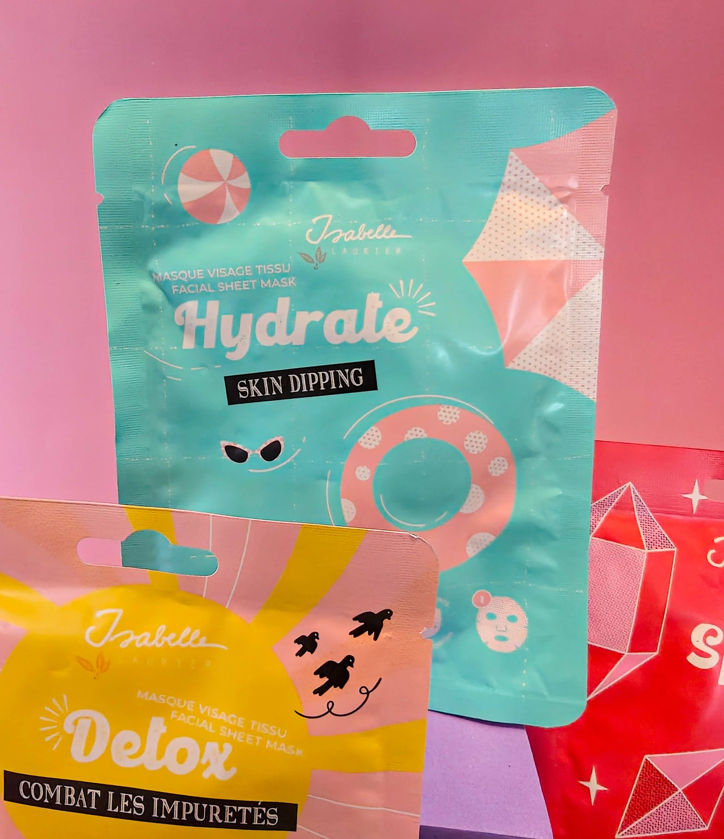 Twee kleurrijke gezichtsmaskers in verpakking tegen roze achtergrond, hydrate en detox thema.
