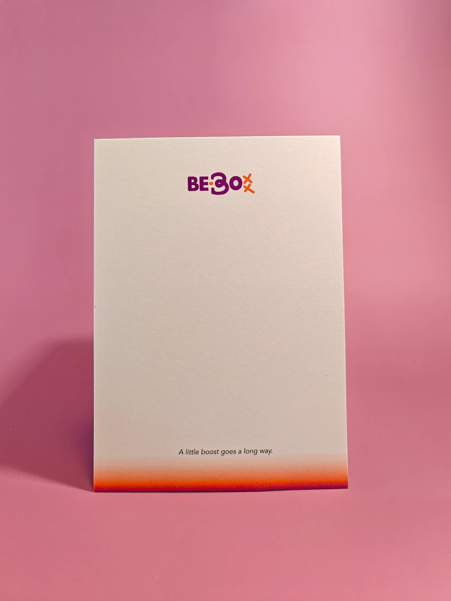 Witte kaart met motiverende tekst en kleurrijke rand op roze achtergrond, cadeau box kaartje