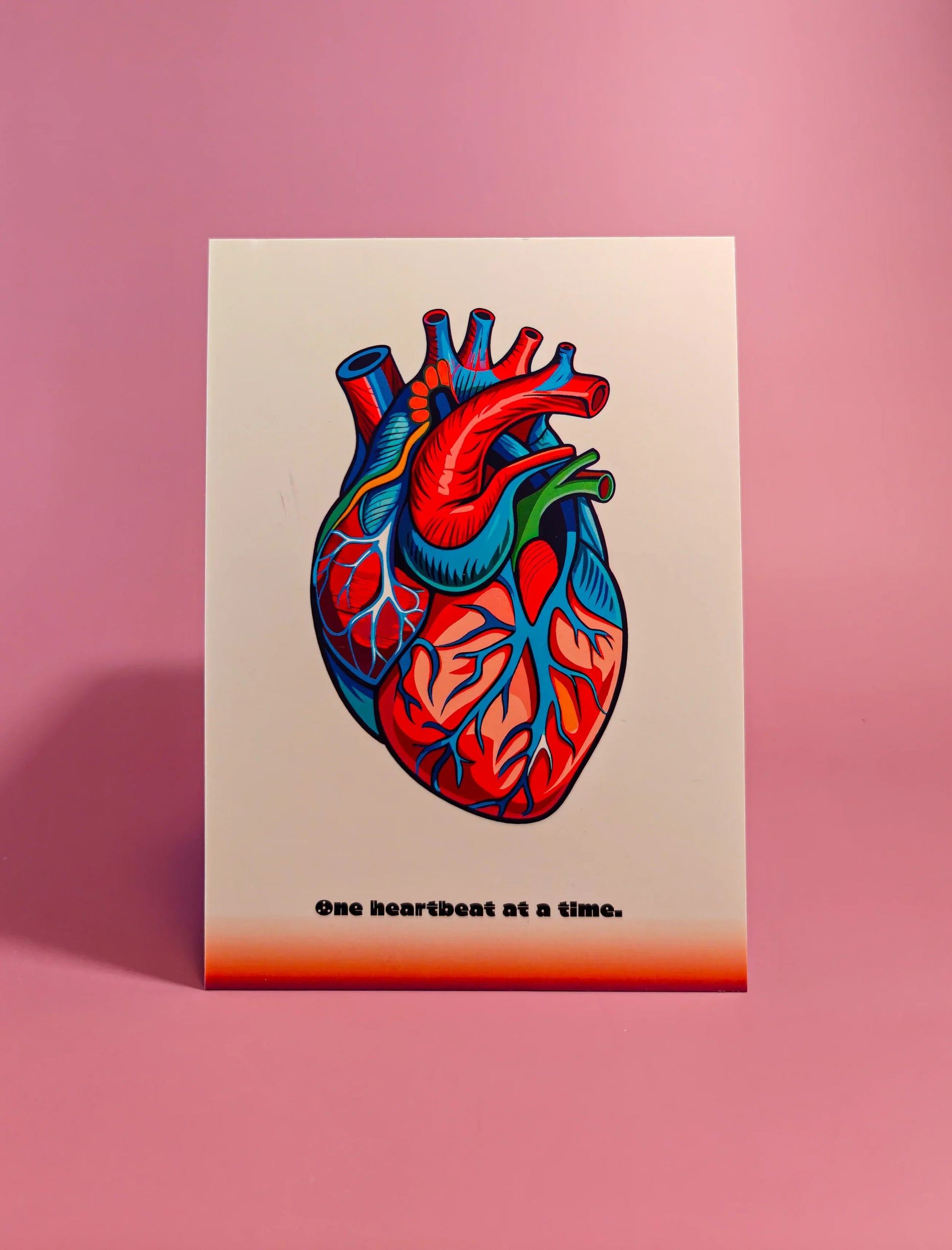 Kaart met kleurrijke anatomisch hart illustratie op roze achtergrond, tekst één hartslag tegelijk