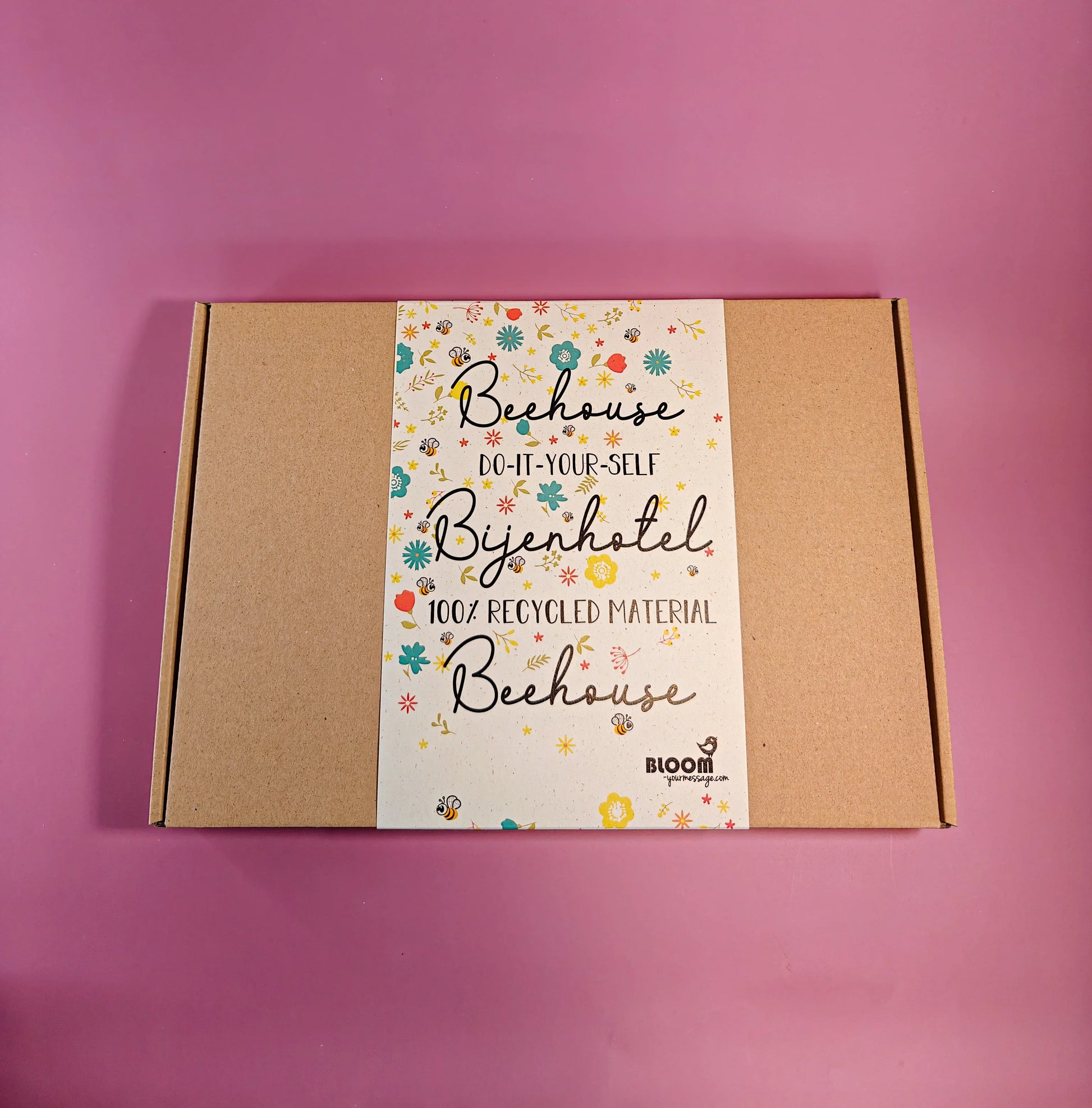 Do-it-yourself bijenhotel bouwpakket in kartonnen doos, 100% gerecycled materiaal op roze ondergrond.