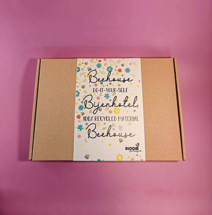 Do-it-yourself bijenhotel bouwpakket in kartonnen doos, 100% gerecycled materiaal op roze ondergrond.