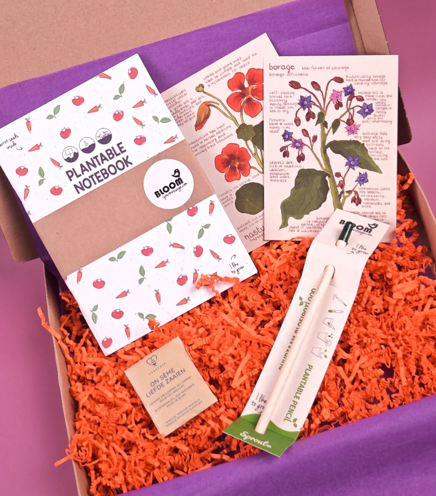 Cadeaubox met plantbaar notitieboek, bloemenkaarten, zaaipotlood en zaadjes op oranje vulmateriaal.